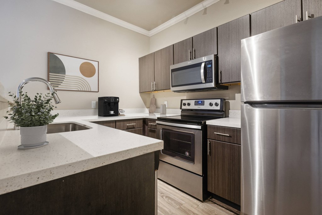 Kitchen A modern kitchen with a stainless steel refrigerator, microwave, and oven.